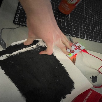 This was an image from in class of my painted conductive paint on a piece of paper. The light from the makey makey is shining showing the flow being completed.